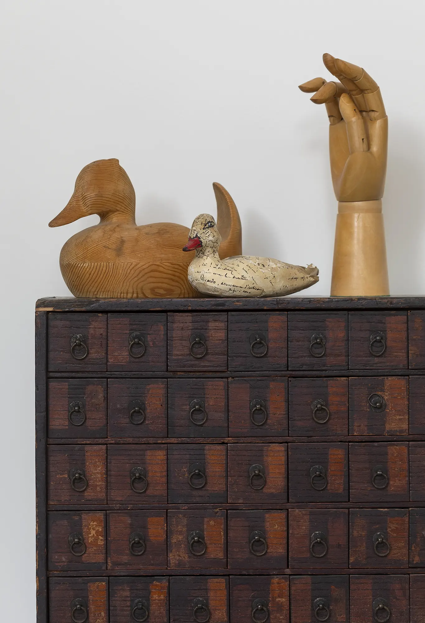 Wooden duck and wooden hand on top of small drawers